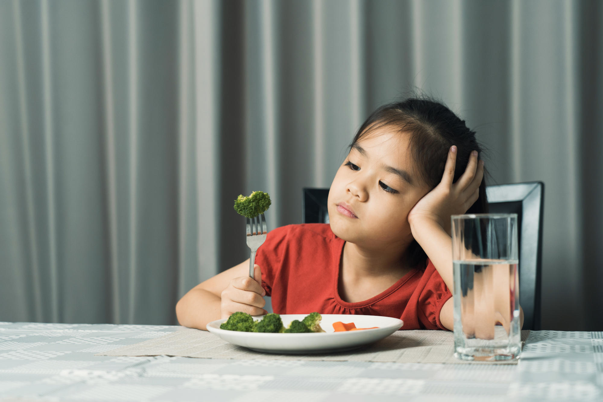 girl refusing to eat her food at the table